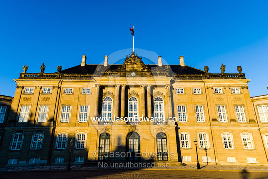 Sunset falls across the facade of the Royal Palace and it's cobblestone courtyard. Amalienborg Palace, Copenhagen, Denmark.