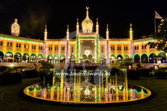 The colourful facade of the Restaurant Nimb at night reflected in a pond. Restaurant Nimb, Tivoli Gardens, Copenhagen, Denmark.