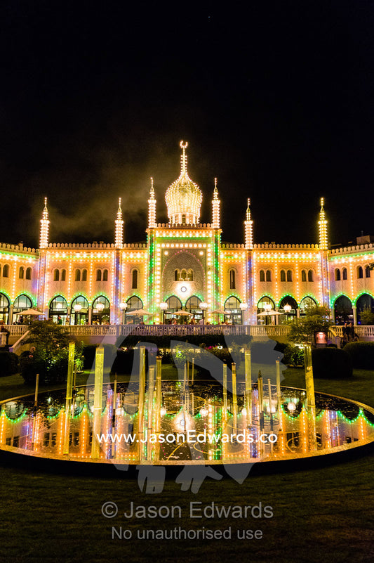 The colourful facade of the Restaurant Nimb at night reflected in a pond. Restaurant Nimb, Tivoli Gardens, Copenhagen, Denmark.