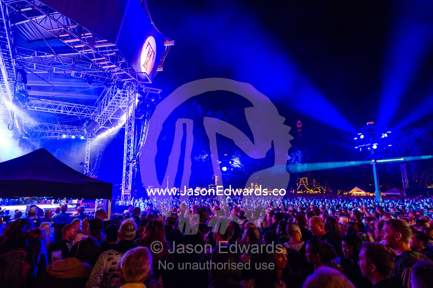 An enormous crowd watching a concert illuminated by neon blue lights. Tivoli Gardens, Copenhagen, Denmark.