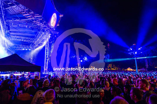 An enormous crowd watching a concert illuminated by neon blue lights. Tivoli Gardens, Copenhagen, Denmark.