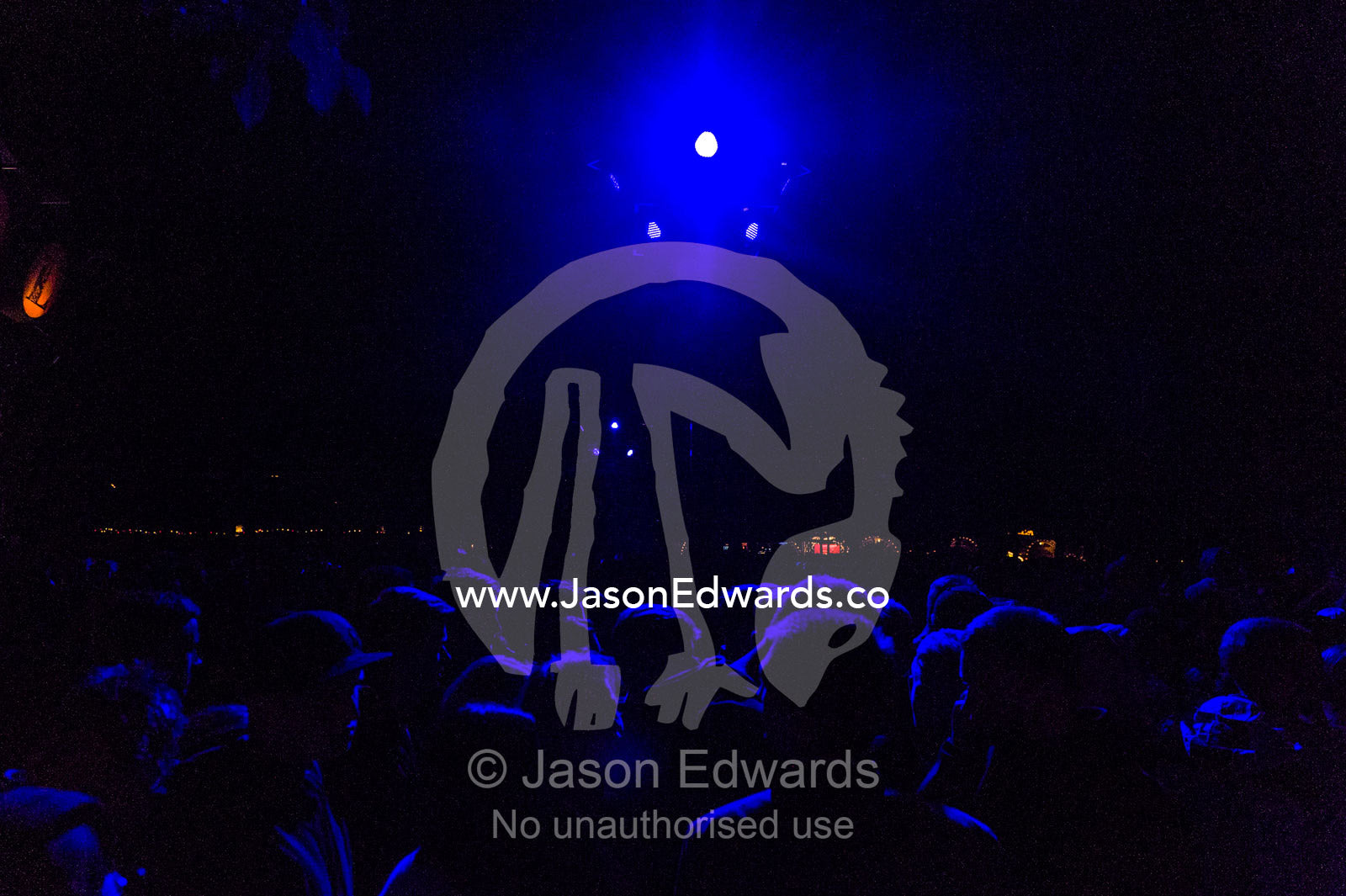 The heads of people in a crowd watching a concert illuminated by neon blue lights. Tivoli Gardens, Copenhagen, Denmark.