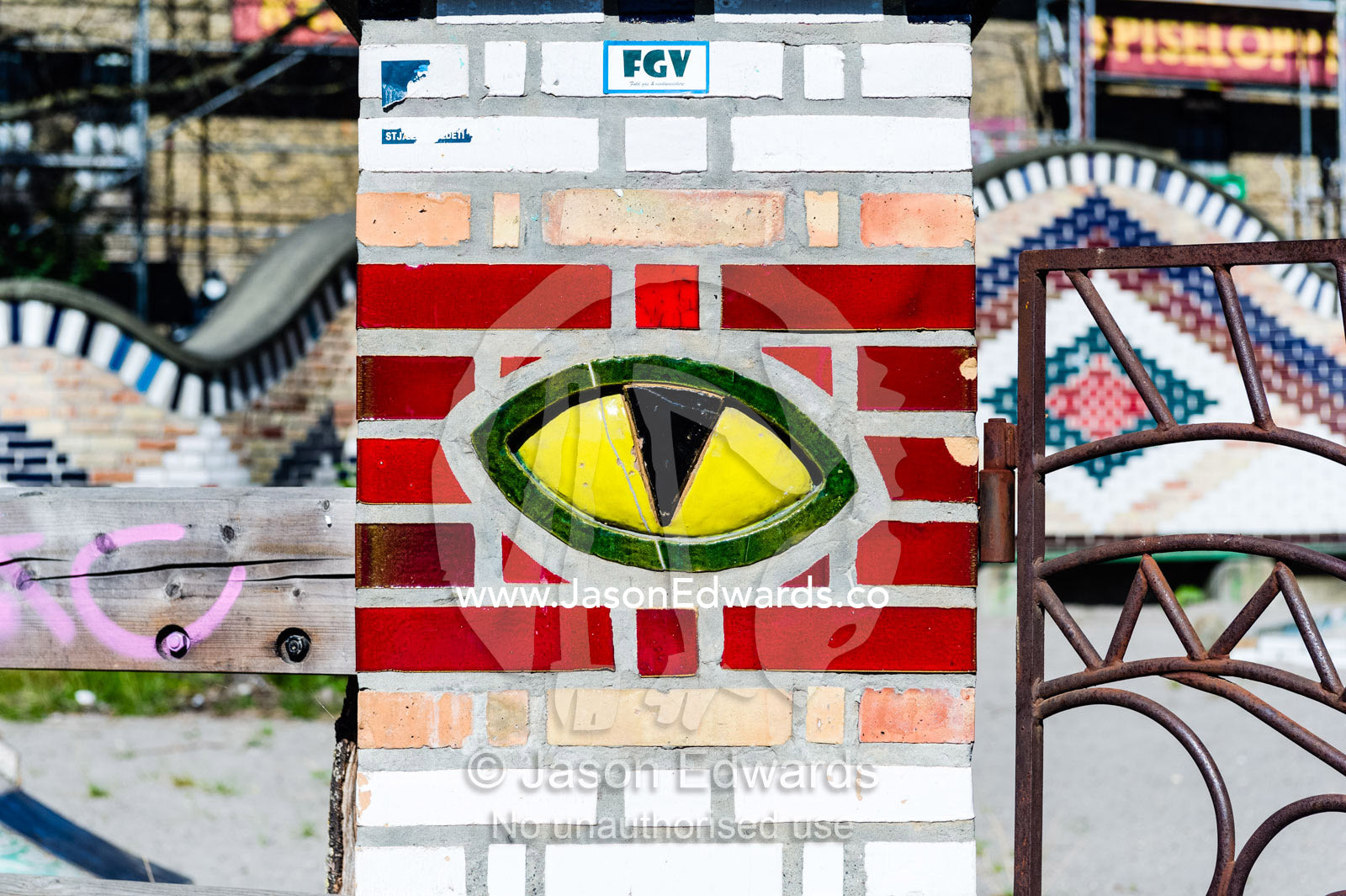 A bright yellow tiled cats eye on a gate pillar. Christiania, Freetown Christiania, Christianshavn, Copenhagen, Denmark.