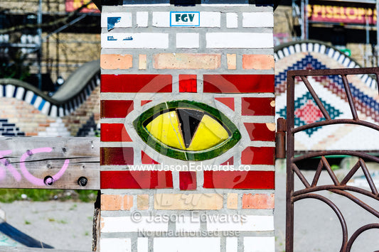 A bright yellow tiled cats eye on a gate pillar. Christiania, Freetown Christiania, Christianshavn, Copenhagen, Denmark.