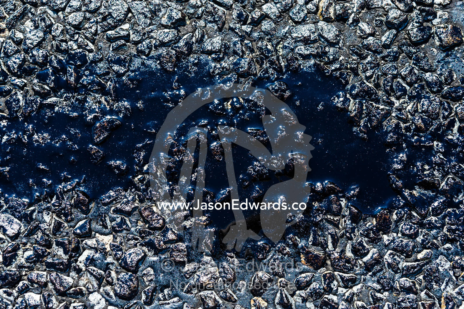 A pool of bitumen melted on a road during a hot Australian summer. Sturt Highway, New South Wales, Australia.