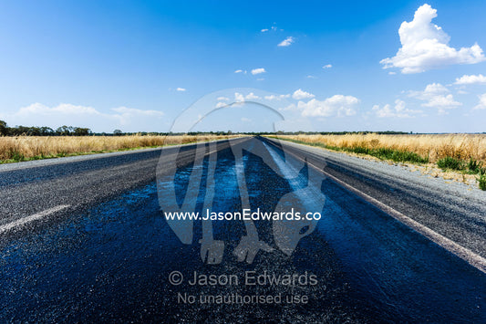 Pools of bitumen melted on a road during a hot Australian summer. Sturt Highway, New South Wales, Australia.