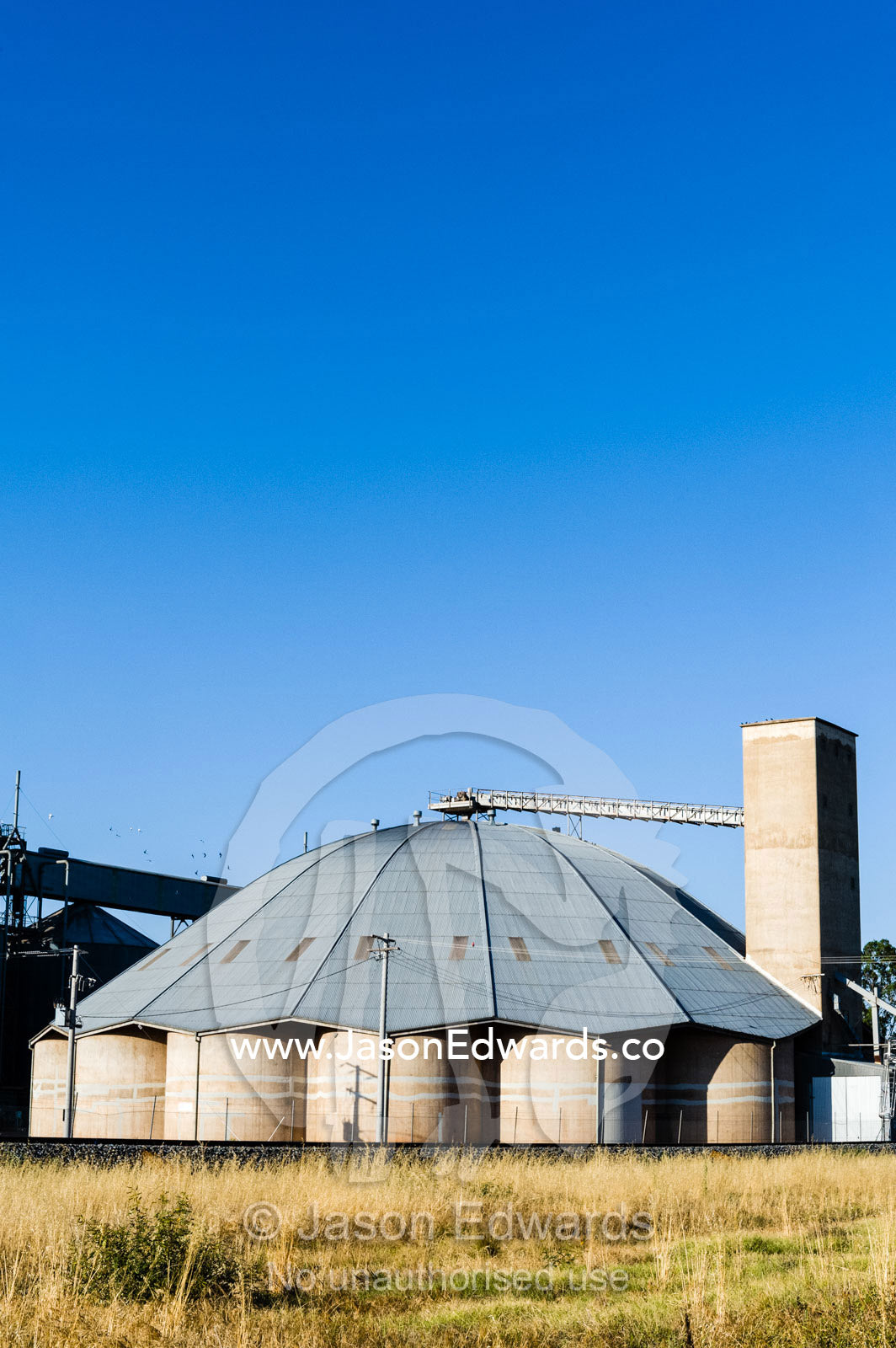 Wheat and grain silos at a rail crossing in a rural town. Narrandera, New South Wales, Australia.