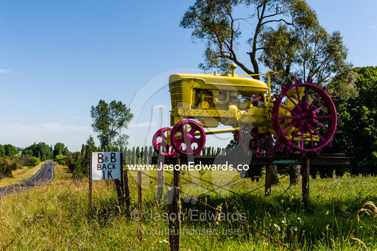 An antique red and yellow tractor at the entrance to a farm. Glen Innes, New South Wales, Australia.