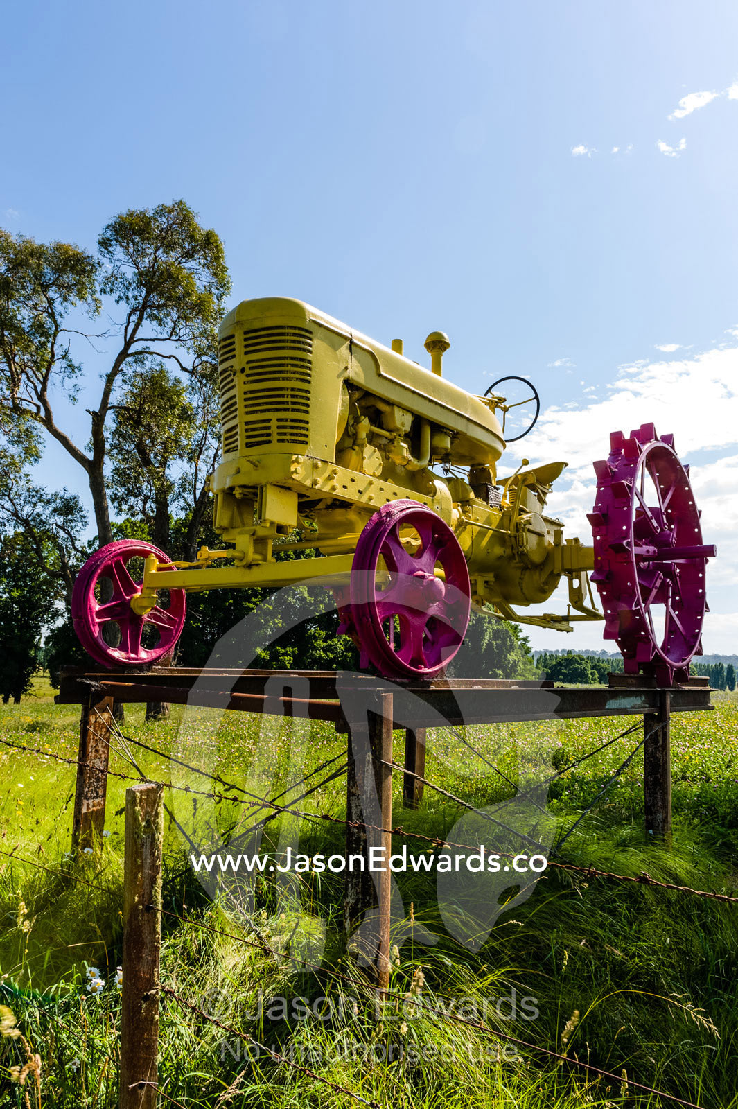 An antique red and yellow tractor at the entrance to a farm. Glen Innes, New South Wales, Australia.