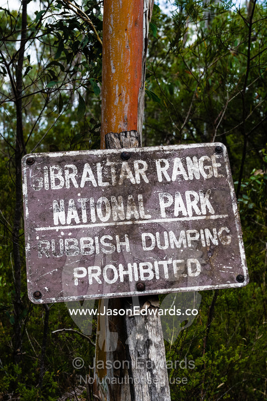 A weathered sign warns of rubbish dumping. Gibraltar Range National Park, New South Wales, Australia.