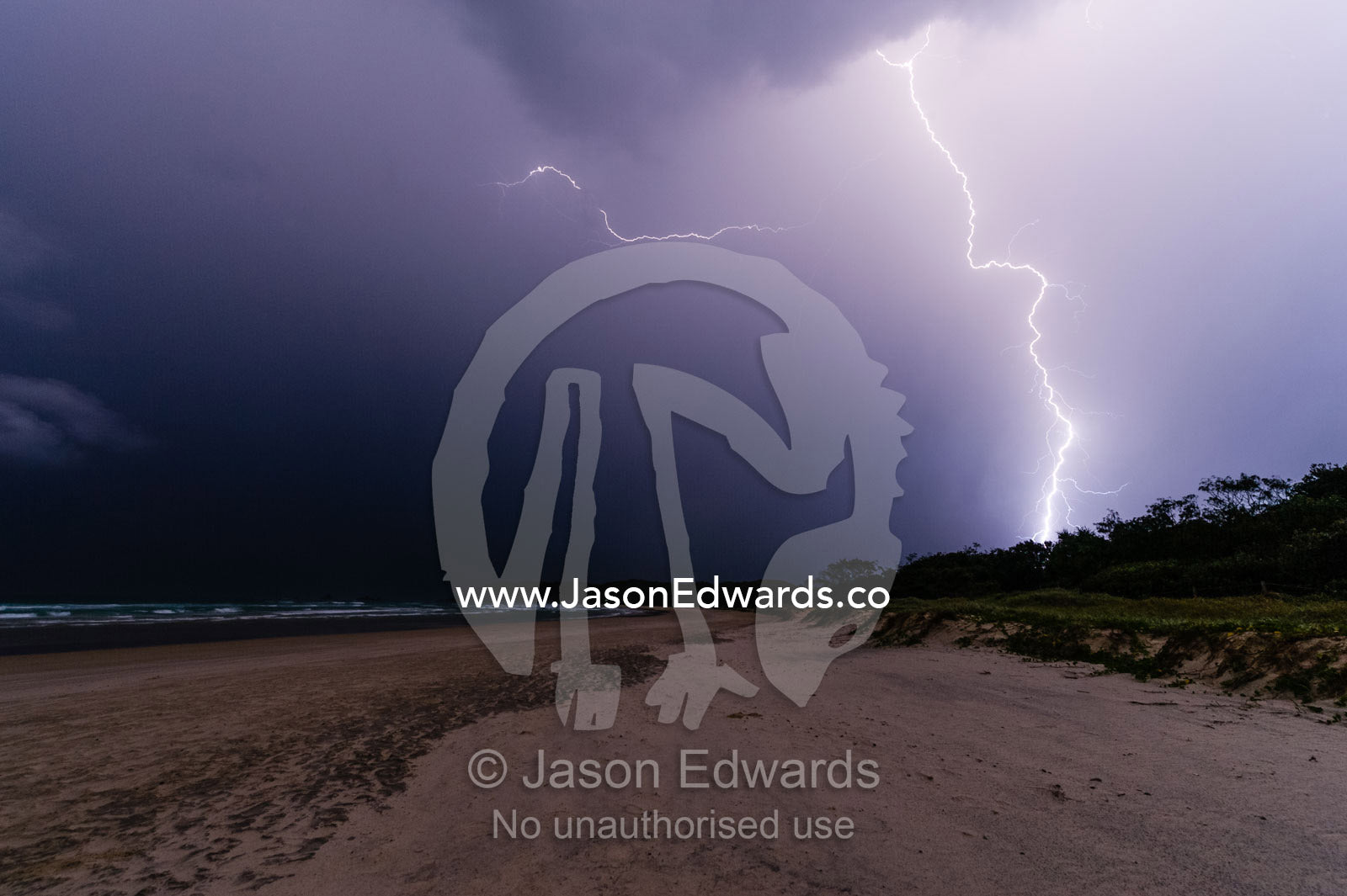 Lightning strikes a sand dune and the ocean during an electrical storm. Suffolk Park, New South Wales, Australia.