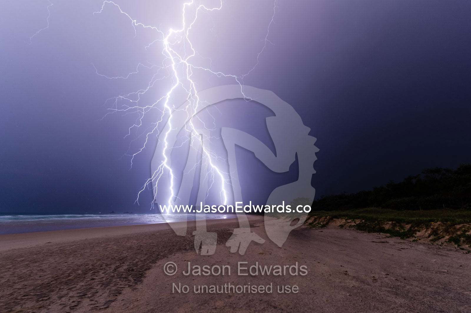 Lightning strikes a sand dune and the ocean during an electrical storm. Suffolk Park, New South Wales, Australia.