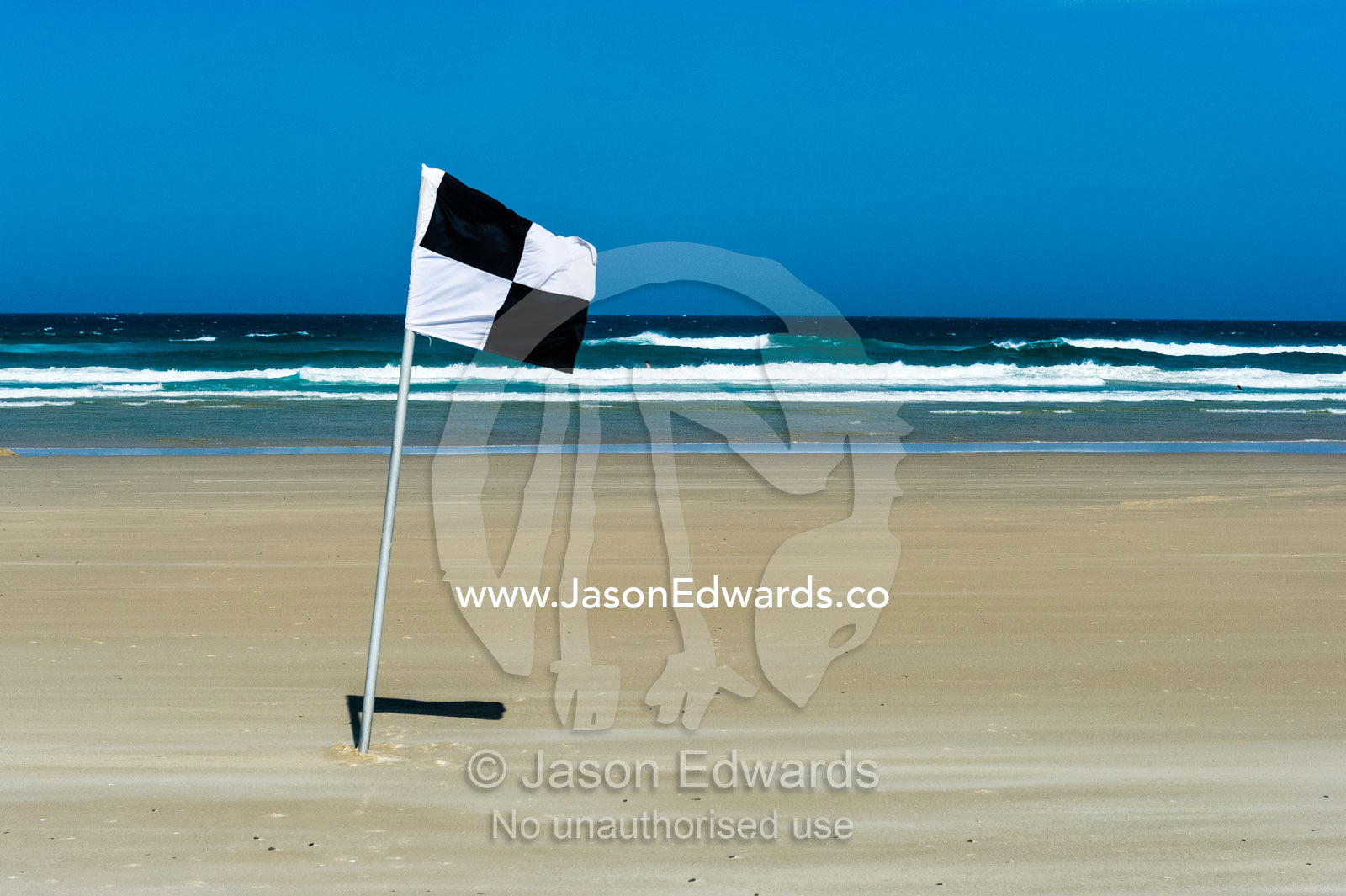 A lifesaving beach flag identifies the surf rescue craft boundary zone. Byron Bay, New South Wales, Australia.