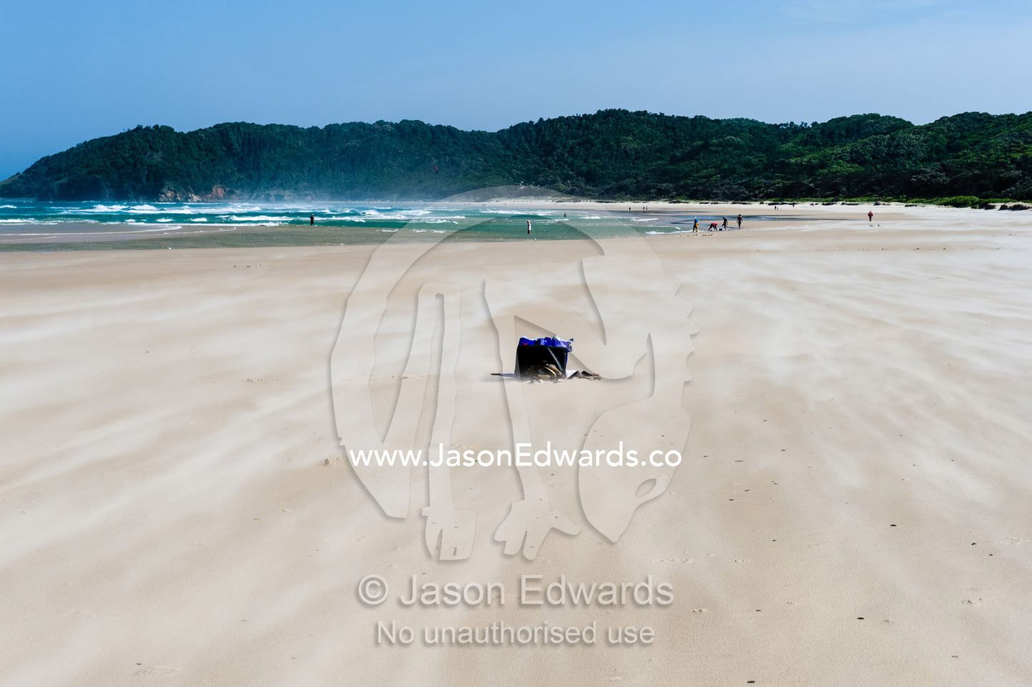 Strong winds blowing sand over a beach bag. Byron Bay, New South Wales, Australia.