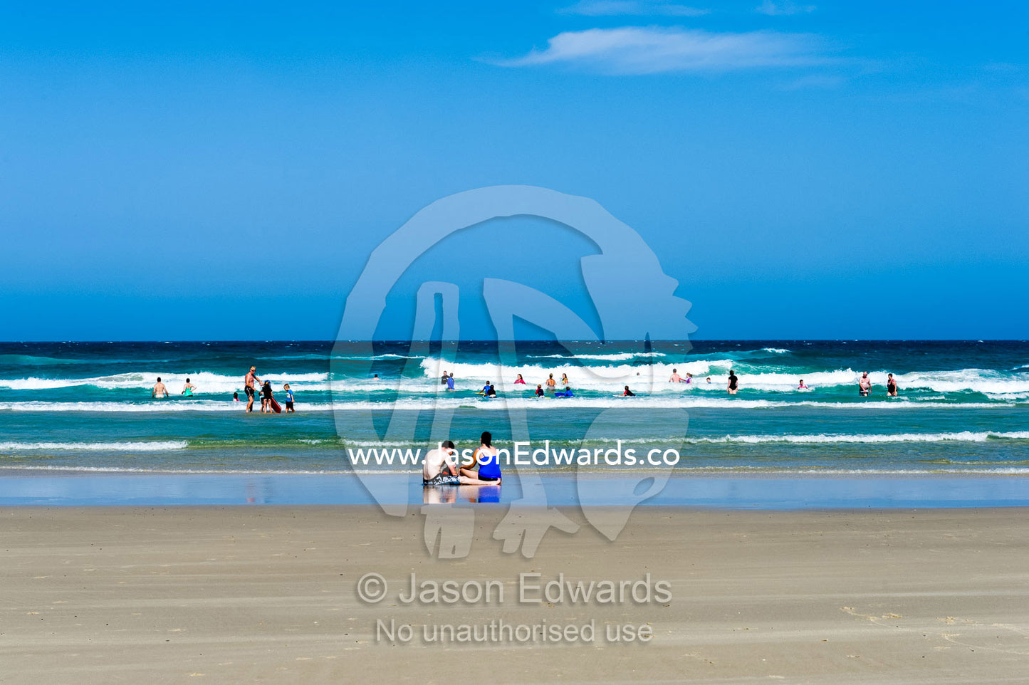People playing on a wide beach at low tide. Byron Bay, New South Wales, Australia.
