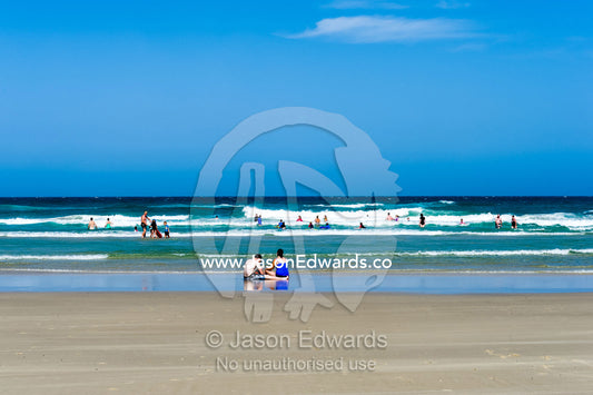 People playing on a wide beach at low tide. Byron Bay, New South Wales, Australia.