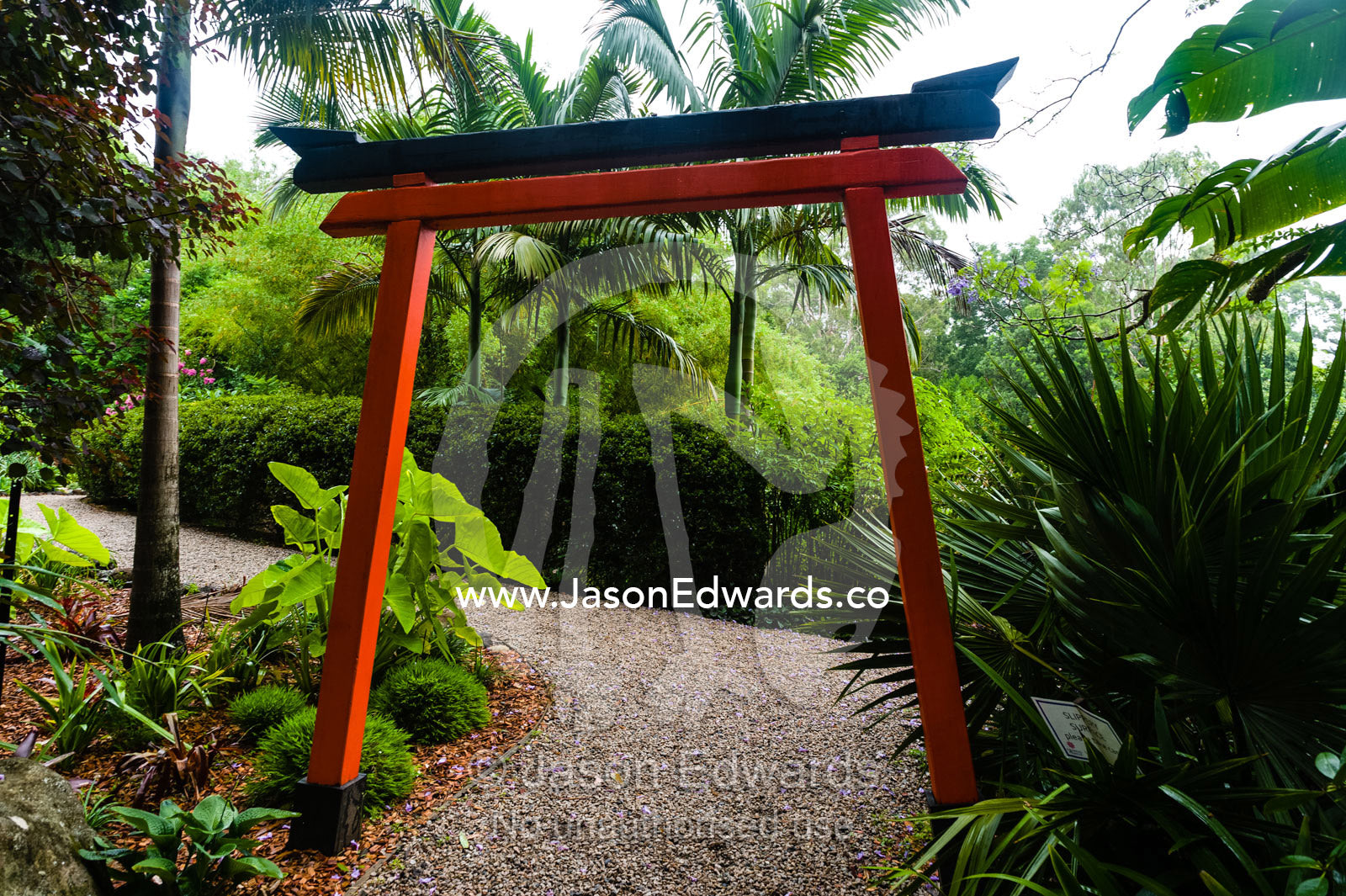 An orange Buddhist torii gate in a botanical garden. Crystal Castle, Shambhala Gardens, Mullumbimby, New South Wales, Australia.