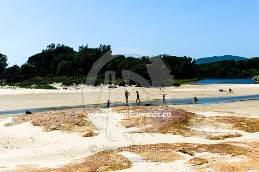 Families and children playing in a tidal inlet at low tide. South West Rocks, New South Wales, Australia.