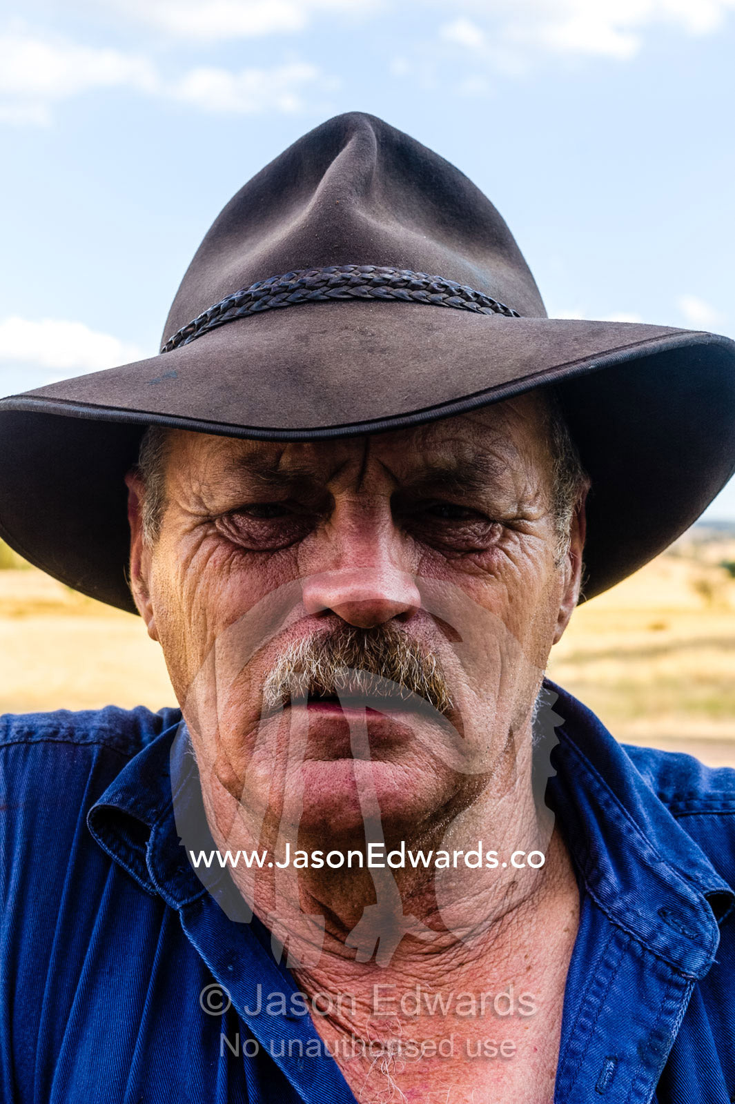 The weathered features of a farmer wearing an akubra slouch hat. Holbrook, New South Wales, Australia.