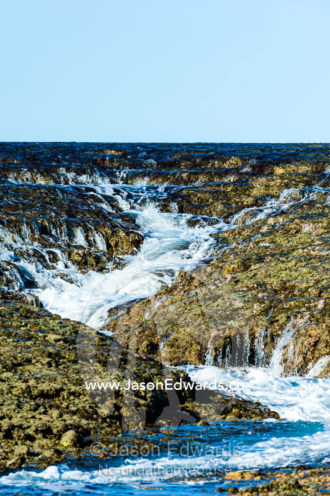 Water cascades from the surface of an exposed coral reef at low tide. Montgomery Reef, Camden Sound, Kimberley Coast, Western Australia, Australia.