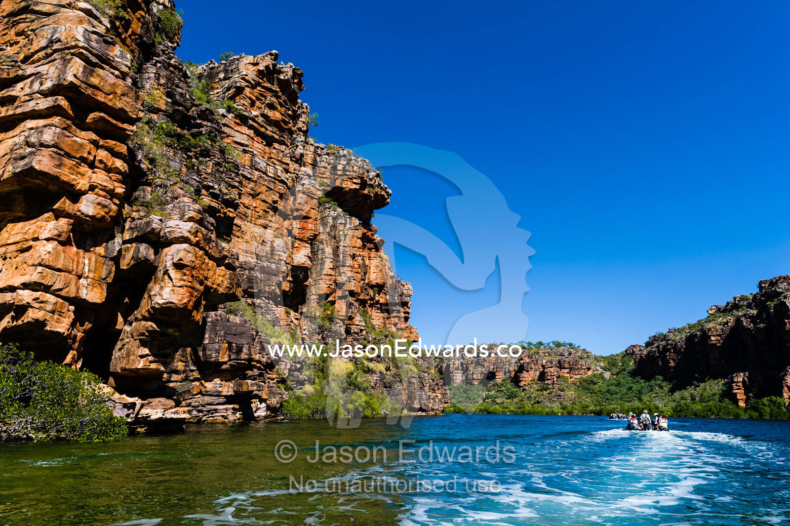 Tourists in a dingy explore the geology of a desert gorge on the Kimberley Coast. King George River, King George Falls, Gardner Plateau, Kimberley Coast, Western Australia, Australia.