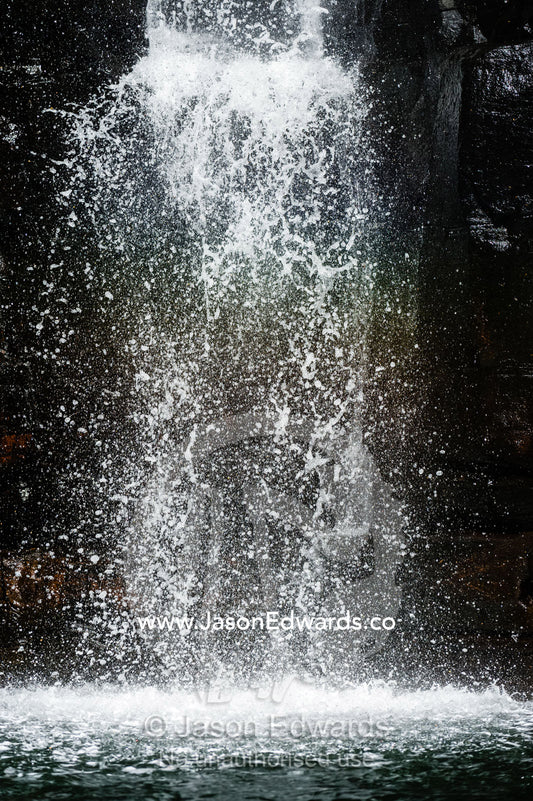 A waterfall cascades down a sheer sandstone cliff covered in cyanobacteria. King George River, King George Falls, Kimberley Coast, Western Australia, Australia.