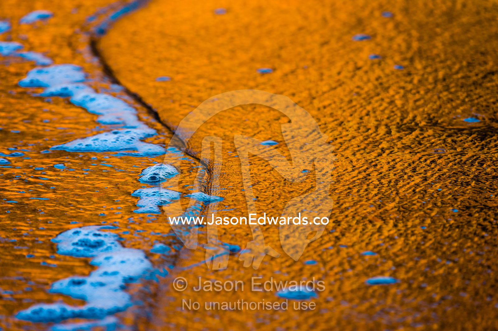 A sandstone cliff reflection in the wet sand on a beach at sunset. Calamity Bay, Koolama Bay, Kimberley Coast, Western Australia, Australia.