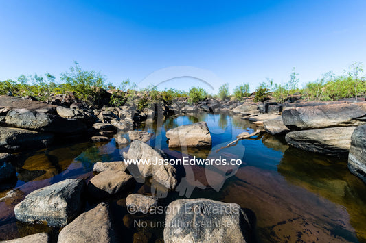 A dwindling waterhole in a riverbed during the dry season. King George River, King George Falls, Gardner Plateau, Kimberley Coast, Western Australia, Australia.