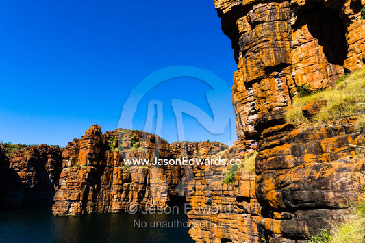 Sheer ochre sandstone canyon walls on a desert coastline. King George River, King George Falls, Gardner Plateau, Kimberley Coast, Western Australia, Australia.