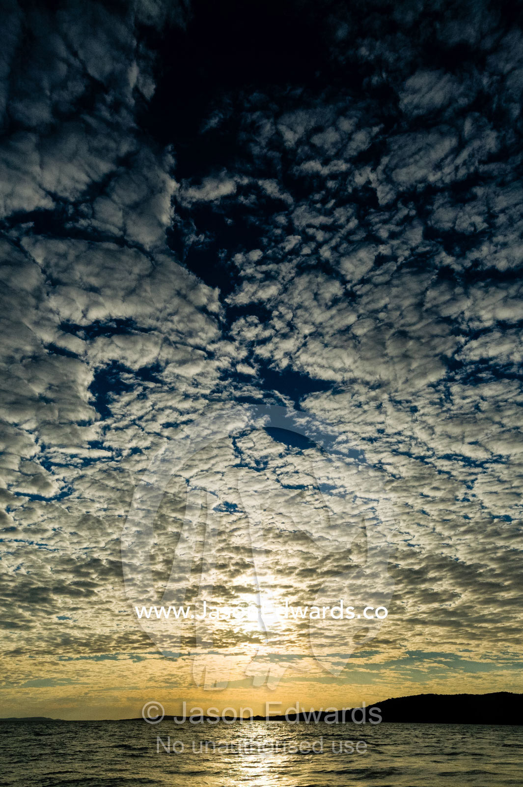 Backlit clouds over the ocean horizon at sunset. Naturalists Island, Wunumpurramarra, Hunter River, Kimberley Coast, Western Australia, Australia.