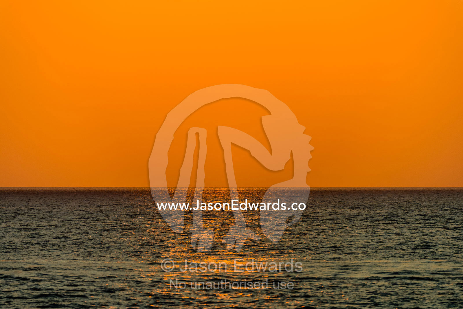 A featureless orange sky over a turquoise ocean at sunset. Lava Flow, Banda Neira, Banda Islands, Maluku Province, Indonesia.