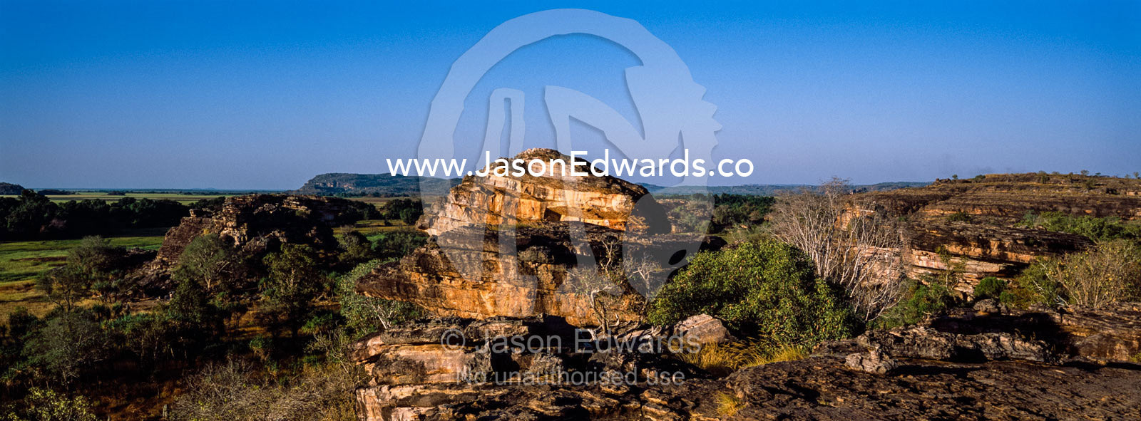 A rugged sandstone escarpment overlooking a floodplain at sunset. Ubirr, Nadab floodplain, Kakadu National Park, Northern Territory, Australia.