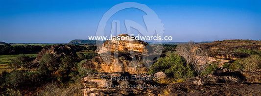 A rugged sandstone escarpment overlooking a floodplain at sunset. Ubirr, Nadab floodplain, Kakadu National Park, Northern Territory, Australia.