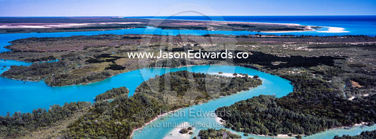 A winding turquoise tidal river flows inland from the sea. Willie Creek Pearl Farm, Broome, Western Australia, Australia.