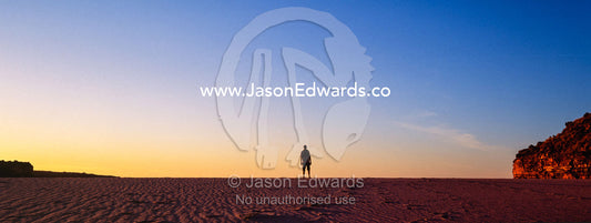 The silhouette of a man standing alone on a deserted beach at sunset. Calamity Bay, Koolama Bay, Kimberley Coast, Western Australia, Australia.