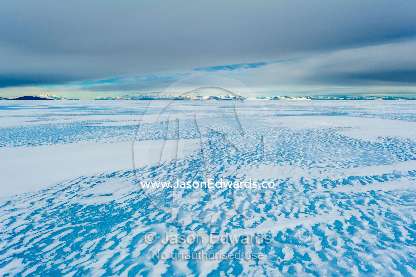 Wind patterns gather in snow drifts on the frozen sea ice in Antarctica. Turtle Rock, Erebus Bay, McMurdo Sound, Ross Island, Antarctica.