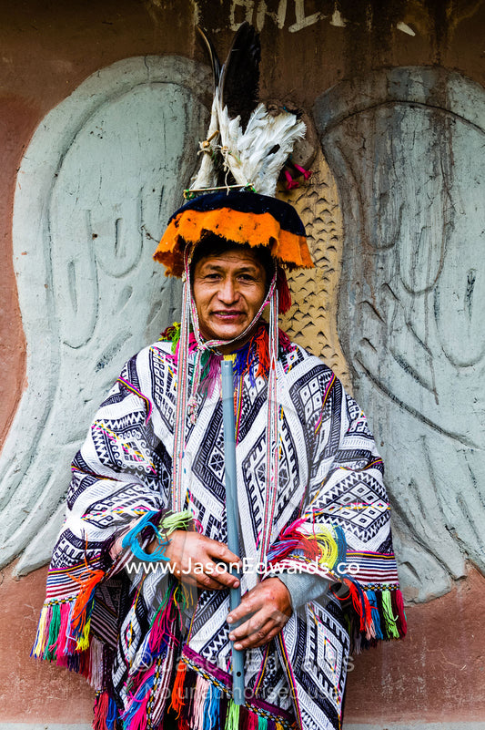 An Amaru man wearing a colorful poncho and a ceremonial montera with feather headdress. Peru.