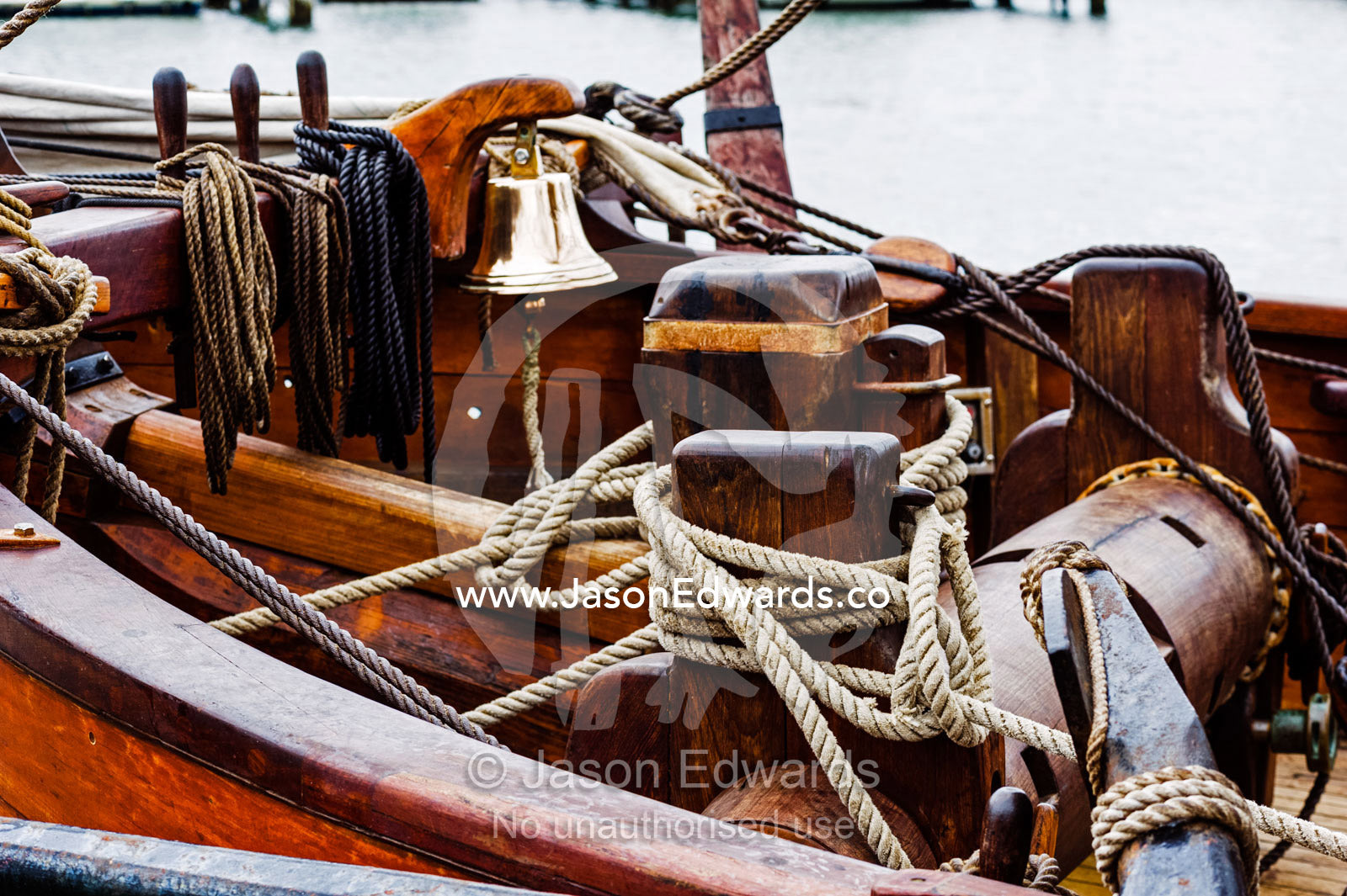 A ship's bell and windlass on the foredeck of an antique timber sailing ship. Melbourne, Victoria, Australia.