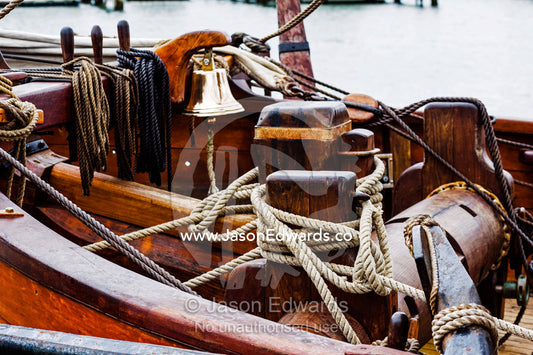A ship's bell and windlass on the foredeck of an antique timber sailing ship. Melbourne, Victoria, Australia.