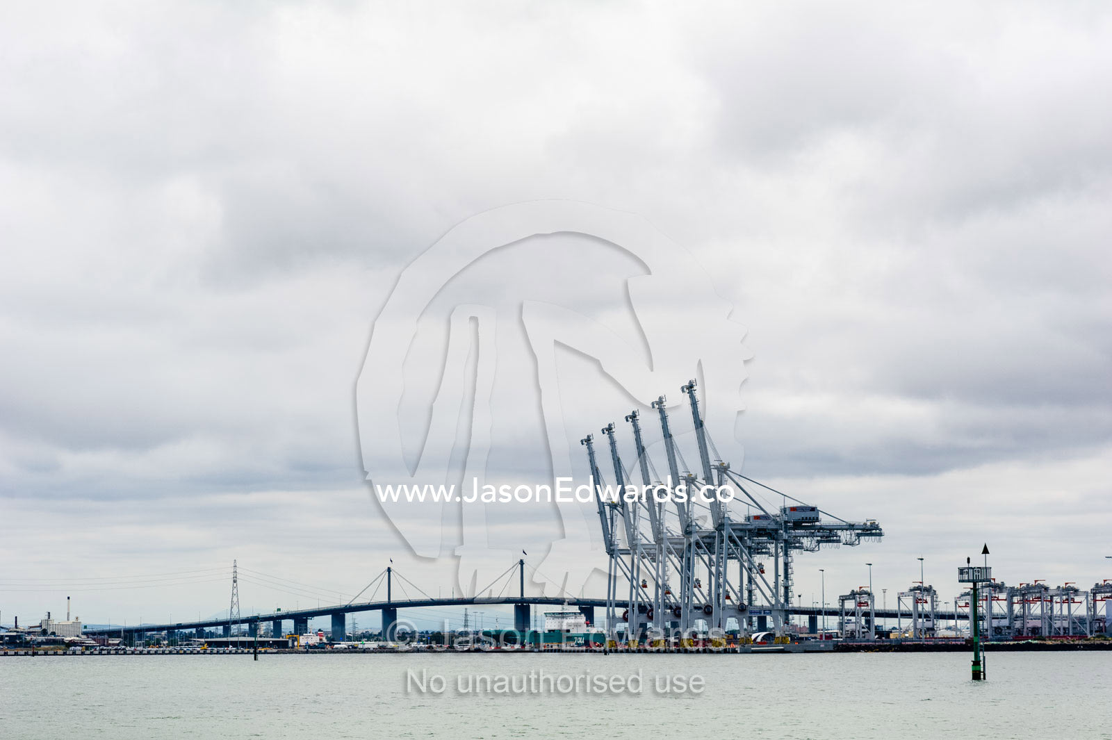 A row of container gantry cranes wait to unload cargo from ships. Melbourne, Victoria, Australia.
