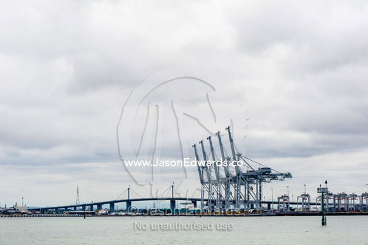A row of container gantry cranes wait to unload cargo from ships. Melbourne, Victoria, Australia.