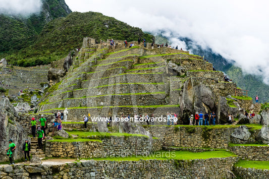 Tourists explore the Inca stone terrace ruins at Macchu Picchu. Peru.