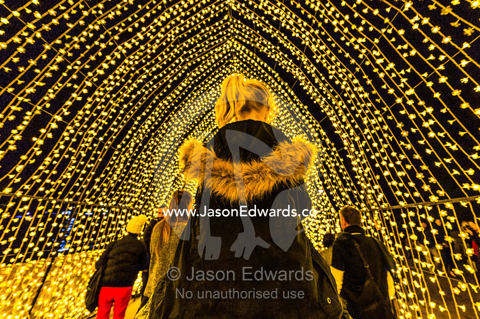 A man carries his daughter on his shoulders through an archway of lights in the Cathedral of Light. Sydney, New South Wales, Australia.