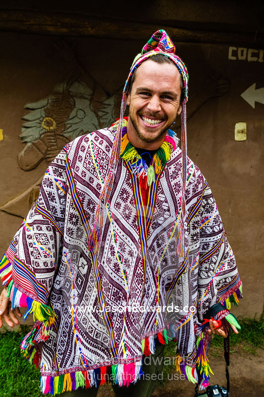 A tourist from the United States wearing a colourful poncho and chullo woven hat. Pisac, Peru.