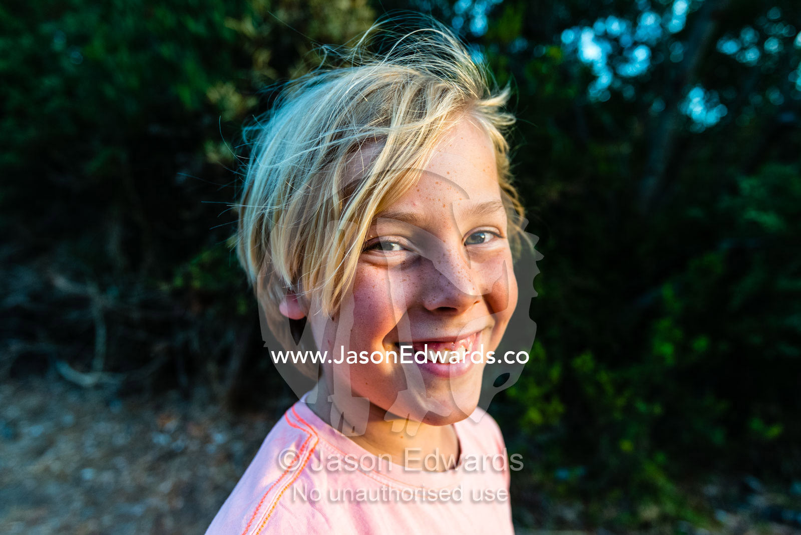 A boy smiles at the camera in summer. Victoria, Australia.