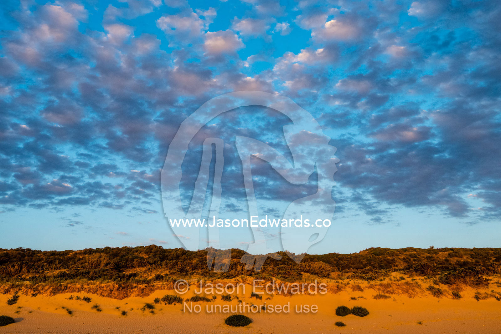 A cluster of clouds gather over a sand dune at sunset. Victoria, Australia.