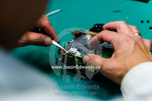 A camera technician repairs the sensor, circuit board and CPU of a digital camera. Victoria, Australia.