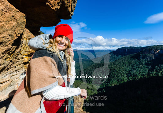A hiker looks over a forest valley from a sandstone cliff. Blue Mountains National Park, New South Wales, Australia.