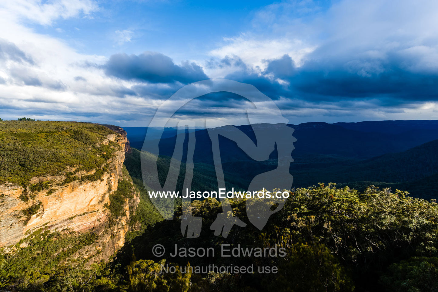 A late afternoon storm descends over a sandstone plateau and eucalyptus forest valley. Blue Mountains National Park, New South Wales, Australia.