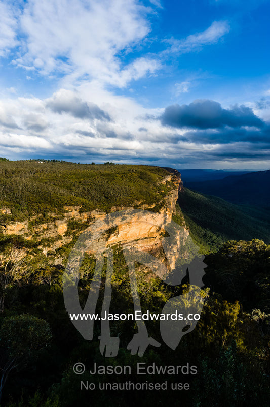 A late afternoon storm descends over a sandstone plateau and eucalyptus forest valley. Blue Mountains National Park, New South Wales, Australia.